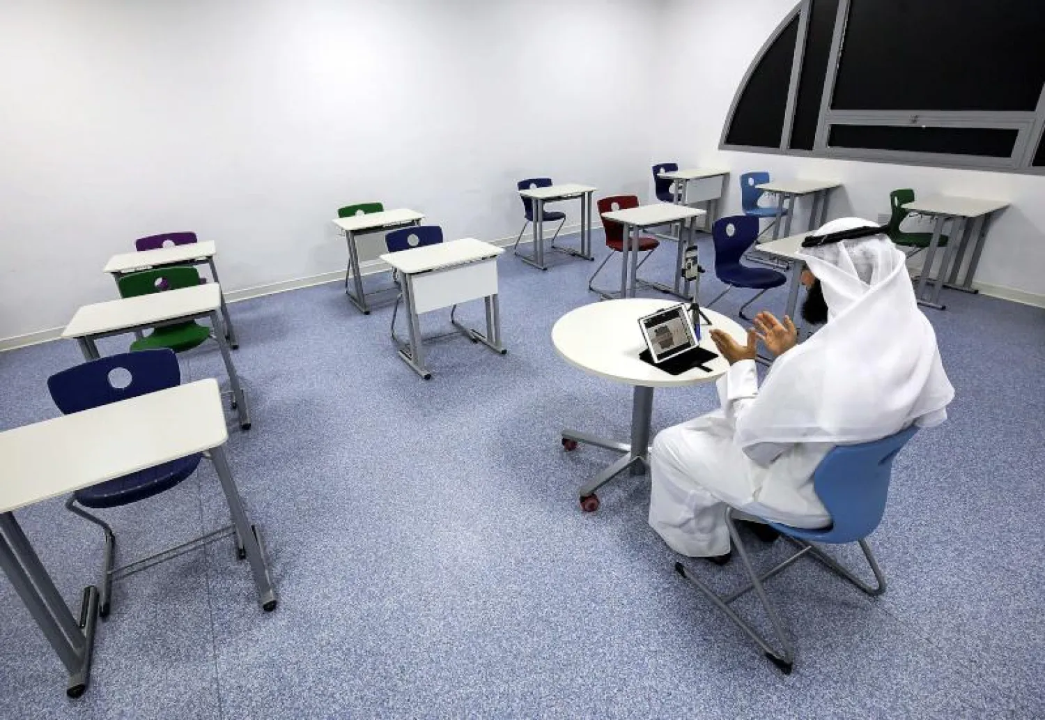 معلم في مدرسة كويتية يعطي صفاً افتراضياً للطلاب في اليوم الأول من بدء الدراسة (أ.ف.ب)