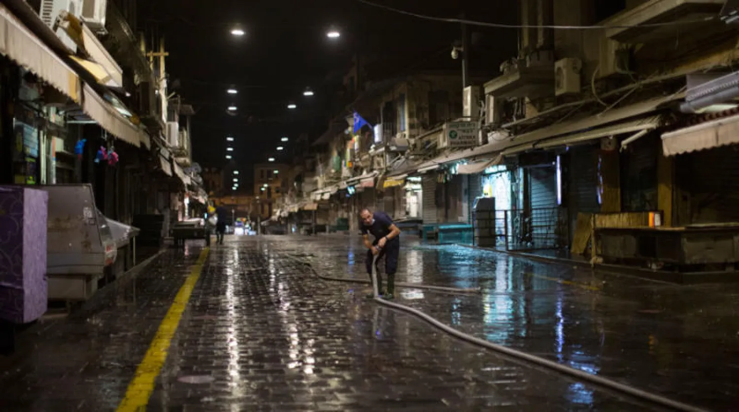 عامل يرش بالماء والمعقمات ممراً في سوق بالقدس بعد الإغلاق ليلة الجمعة استعداداً لعطلة السبت عند اليهود (أ.ب)