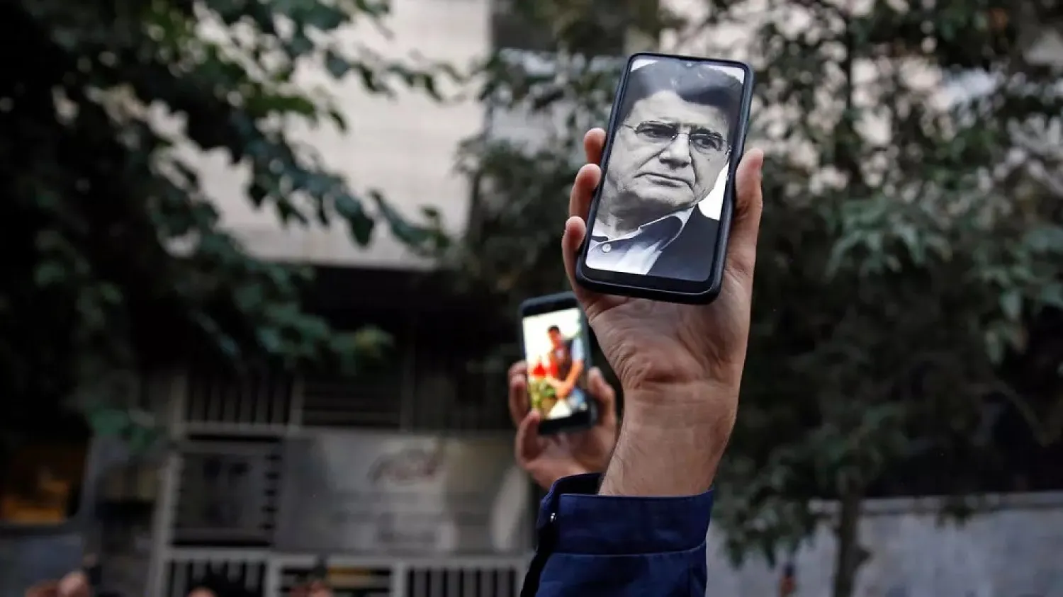 Fans of Iranian musician Mohammad-Reza Shajarian hold up his image on a phone as they mourn his death. (AFP)