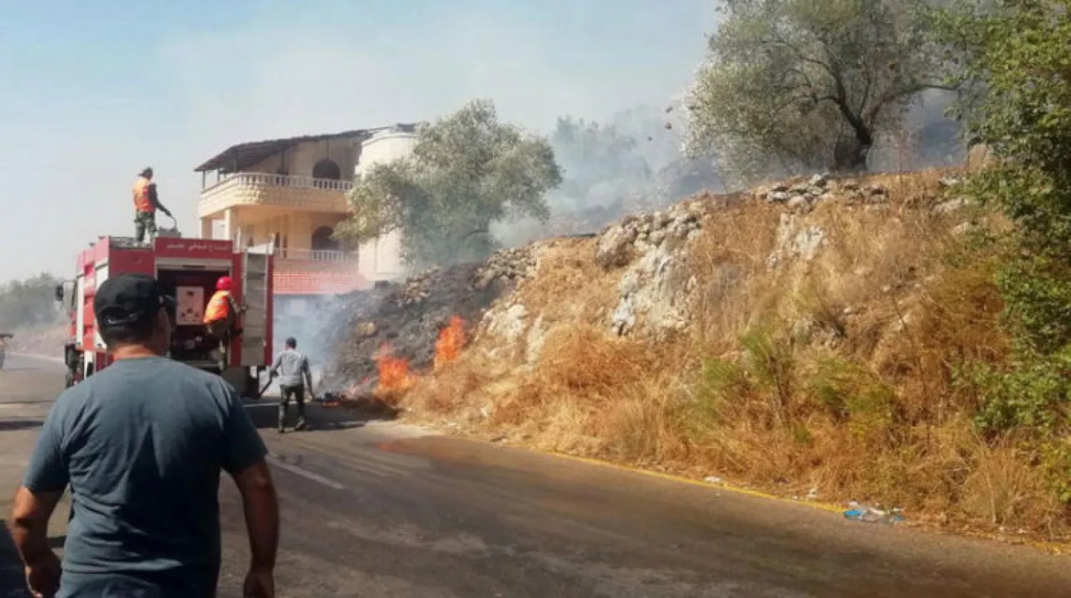 عناصر من الدفاع المدني يحاولون إطفاء حريق في ريف اللاذقية أمس (إ.ب.أ)