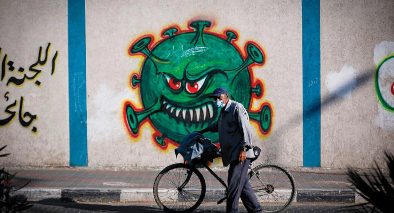 رجل من غزة يسير في القطاع المحاصر بالوباء والضغوط المالية (أ.ف.ب)