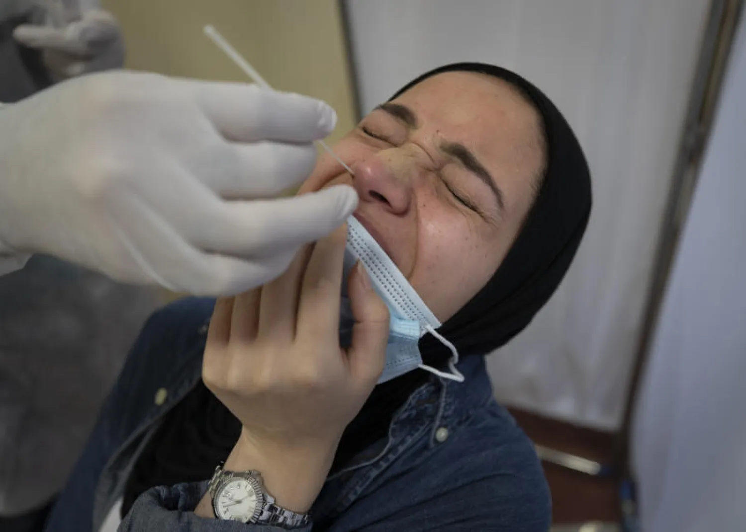 عامل رعاية صحية يأخذ عينة مسحة أنف من امرأة فلسطينية في مركز اختبار «كورونا» بمجمع رام الله  بالضفة الغربية (أ.ب)