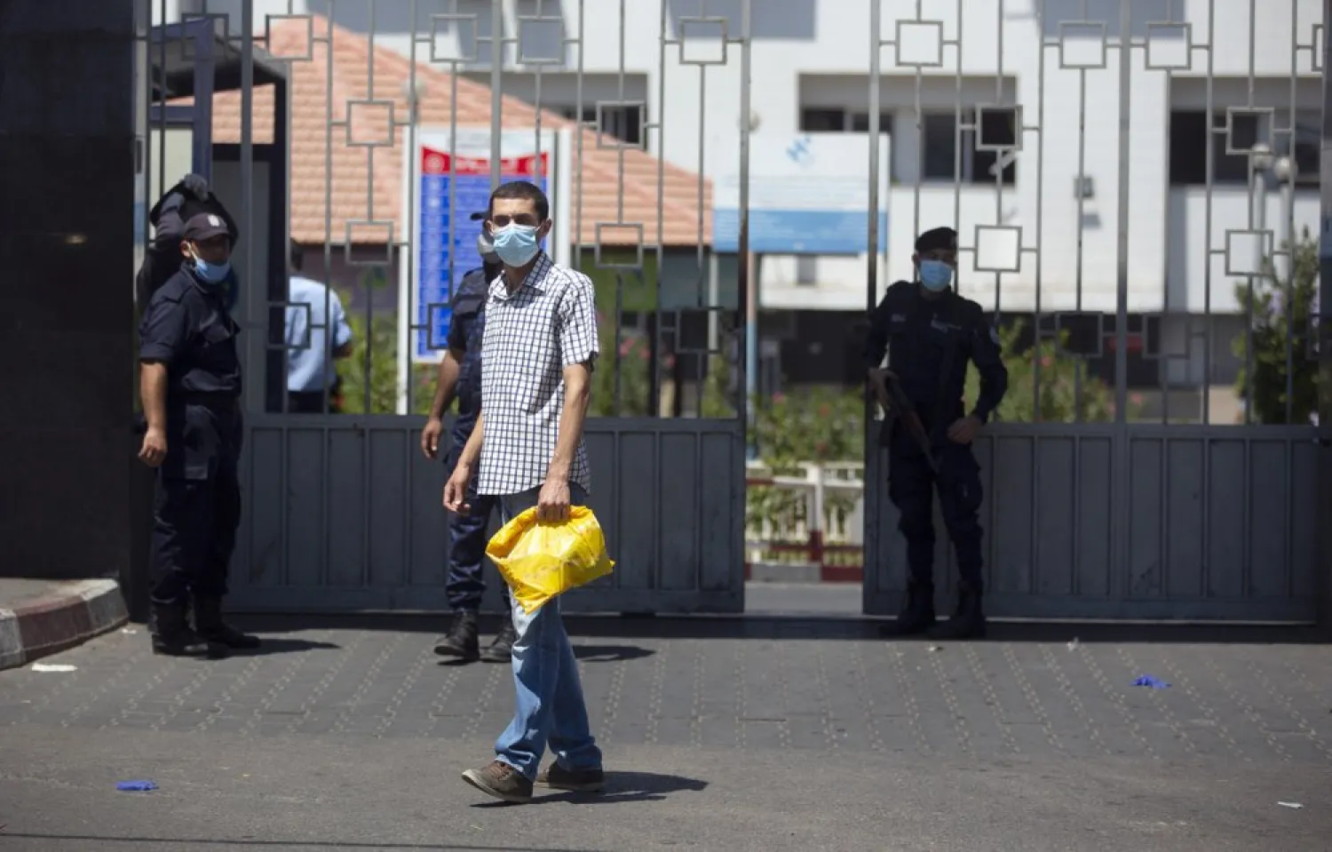 A Palestinian man walks next to Hamas police officers at the entrance of the Shifa Hospital where coronavirus cases were discovered, in Gaza City, Aug. 26, 2020. (AP)