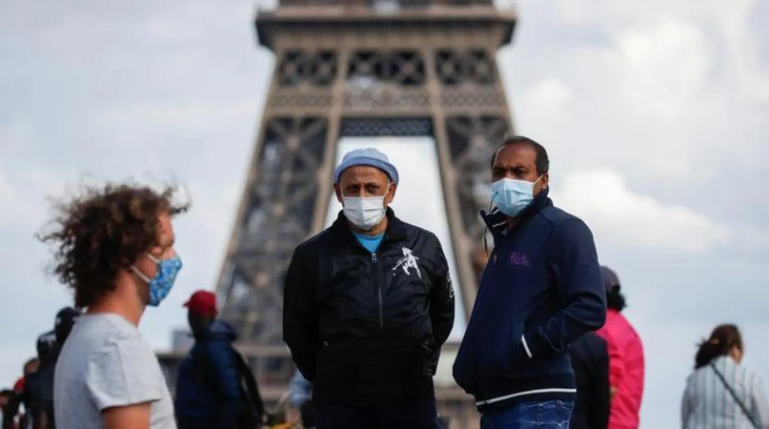 Paris’te Eyfel Kulesi’nin önündeki koruyucu maske takan insanlar (Reuters)