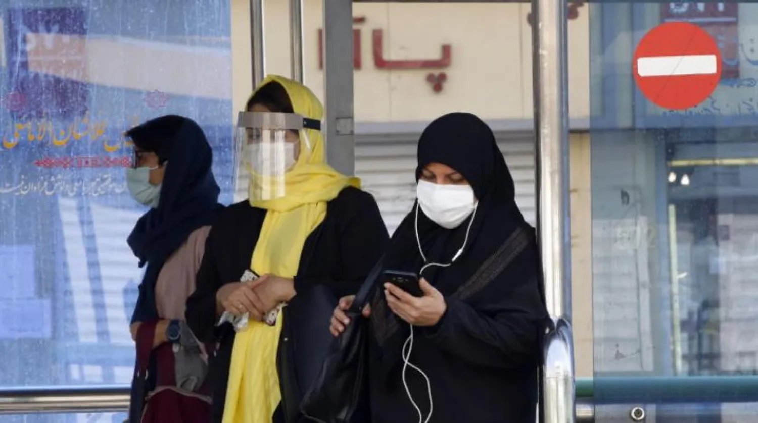 Tahran’daki bir caddede bulunan otobüs durağında maske takan İranlı kadınlar (EPA)