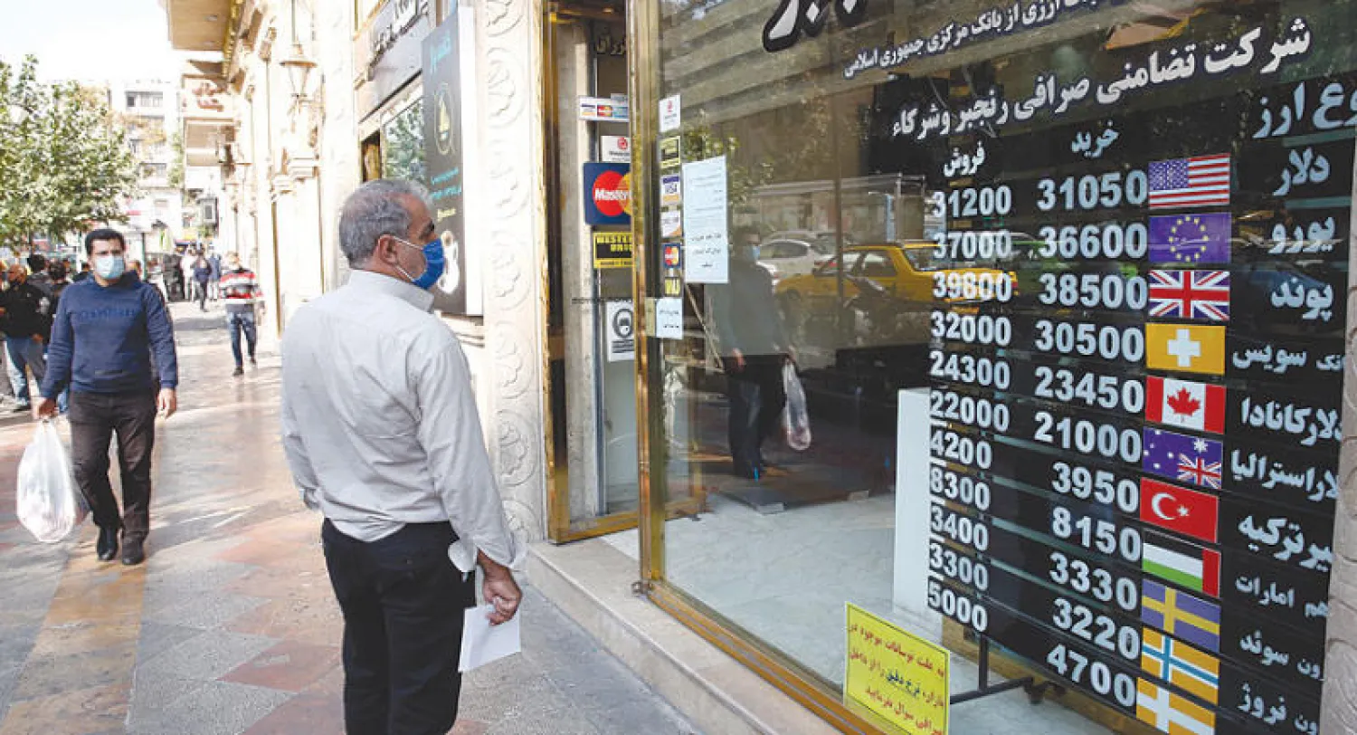 لوحة تظهر أسعار العملات في طهران أمس حيث واصل الريال الإيراني تراجعه القياسي (إ.ب.أ)