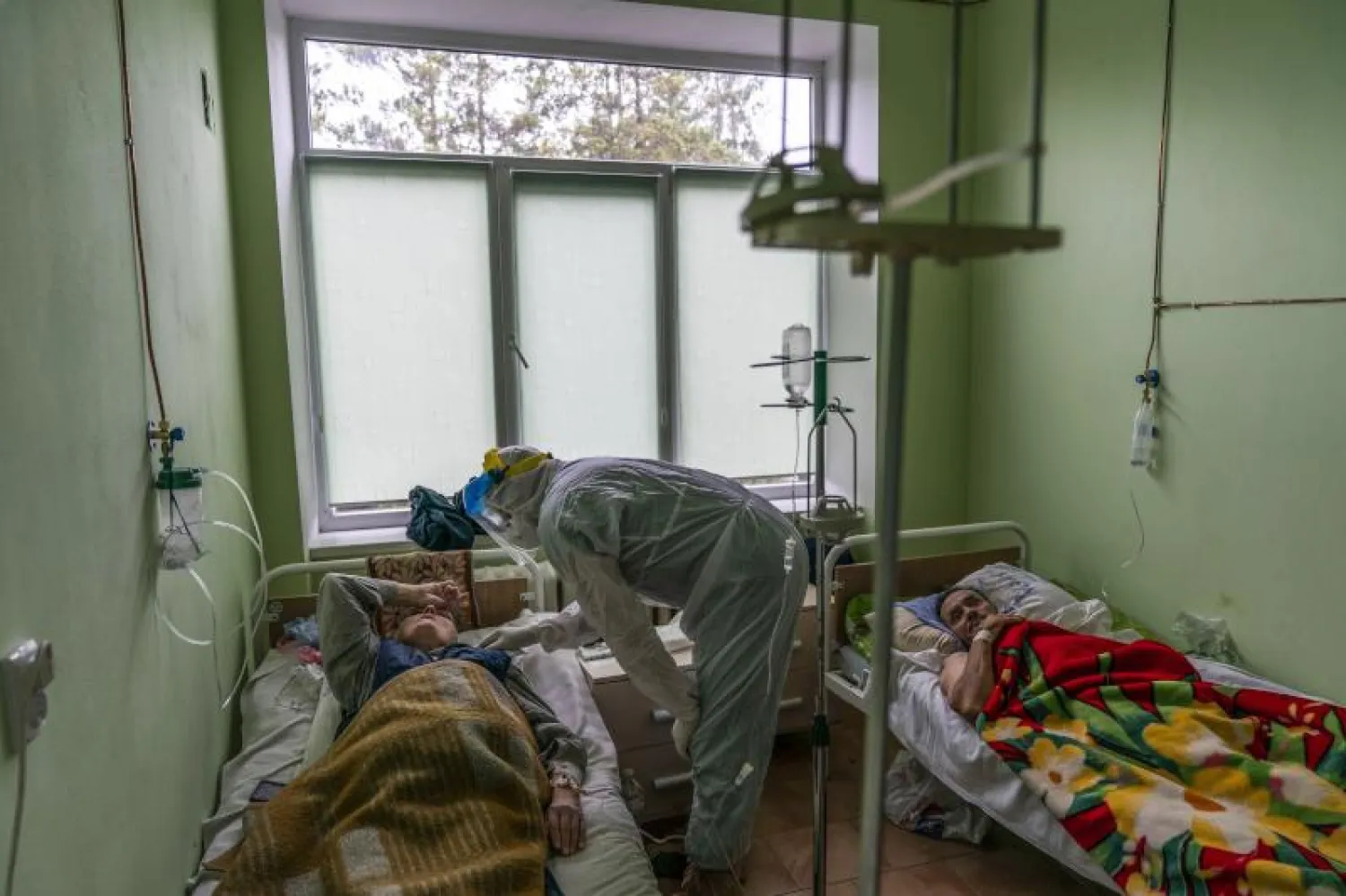 طبيب يتحدث مع مريض مصاب بكورونا في وحدة العناية المركزة بمستشفى بأوكرانيا (أ.ب)