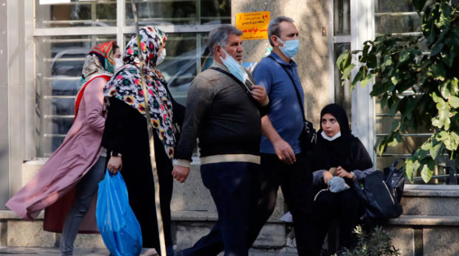 إيرانيون يرتدون كمامات للوقاية من فيروس «كورونا» في شارع وسط طهران (إ.ب.أ)