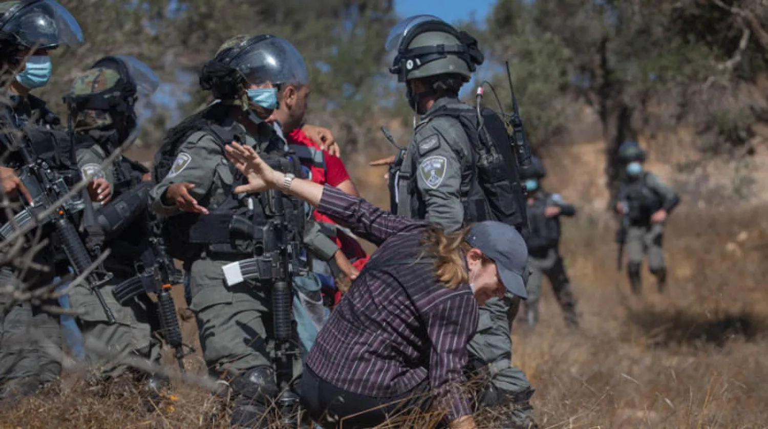 قوات إسرائيلية تدفع امرأة فلسطينية حاولت مع محتجين الوصول إلى بساتين زيتون قرية قرب رام الله (أ.ب)