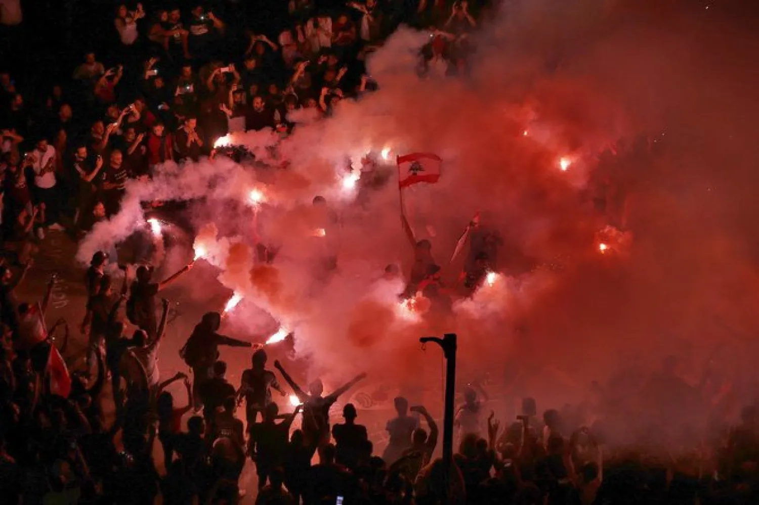 In this Sunday, Nov. 3, 2019 file photo, anti-government protesters light flares and chant slogans against the Lebanese government, in Beirut, Lebanon. A year ago, hundreds of thousands of Lebanese took to the streets in protests nationwide that raised hopes among many for a change in a political elite that over that decades has run the country into the ground. (AP Photo/Bilal Hussein, File)