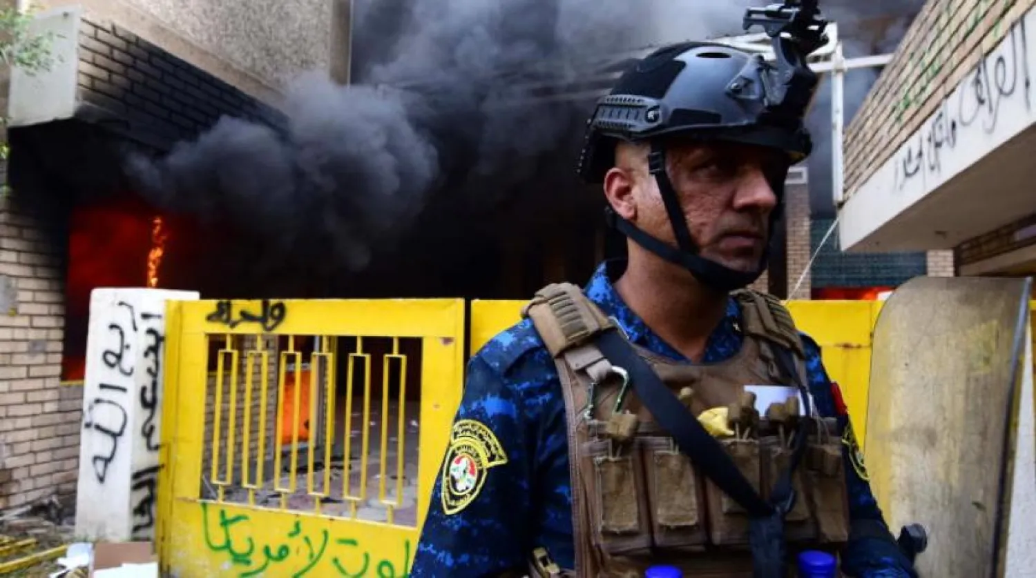 An Iraqi policeman stands guard as smoke rises from the office of Kurdistan Democratic Party (KDP) in Baghdad's Karada district, Iraq on 17 October 2020. EPA/MURTAJA LATEEF