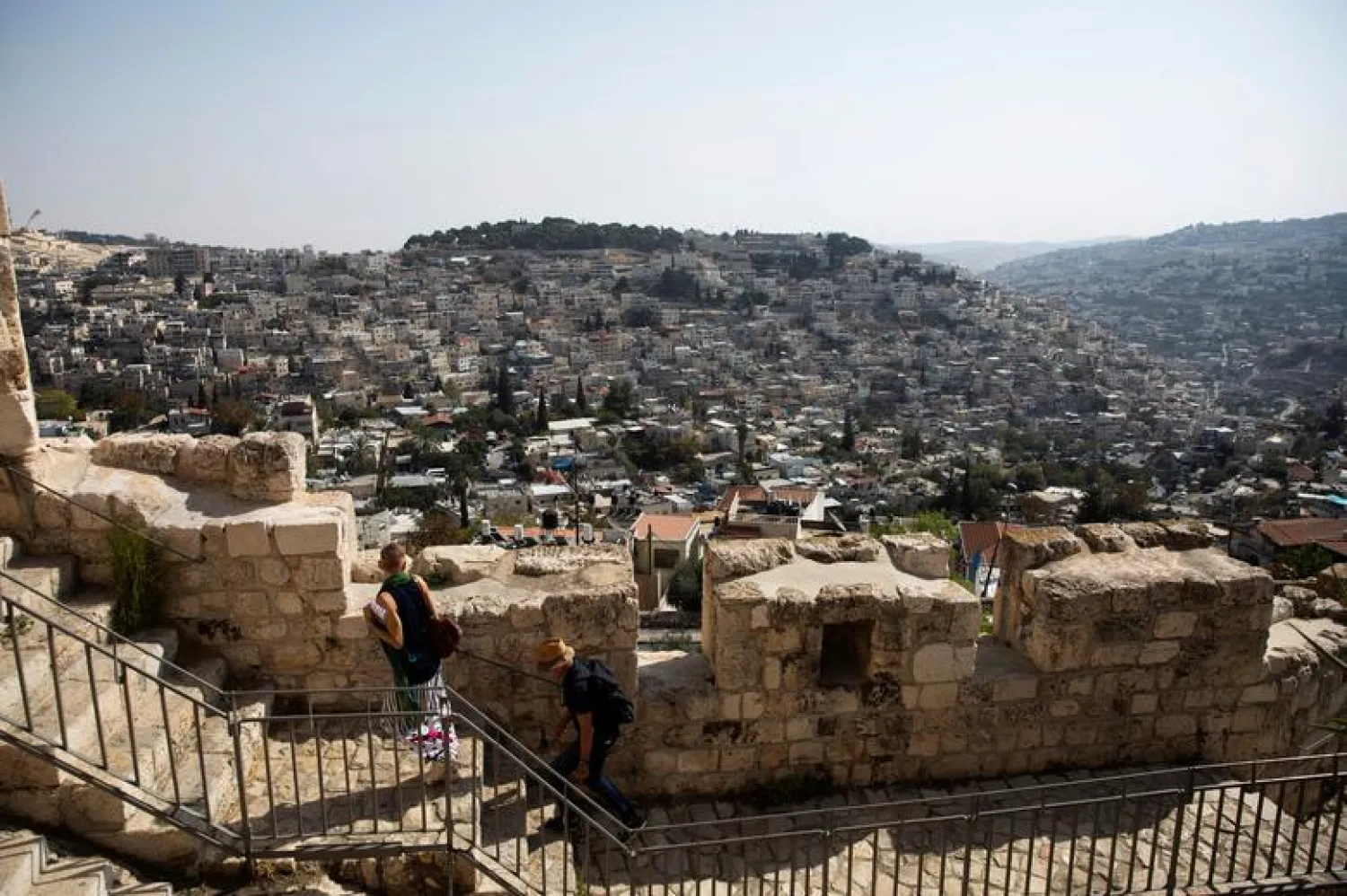  The Palestinian neighborhood of Silwan is seen in the background as people walk on a promenade on the surrounding walls of Jerusalem's Old City November 7, 2019. REUTERS/Ronen Zvulun