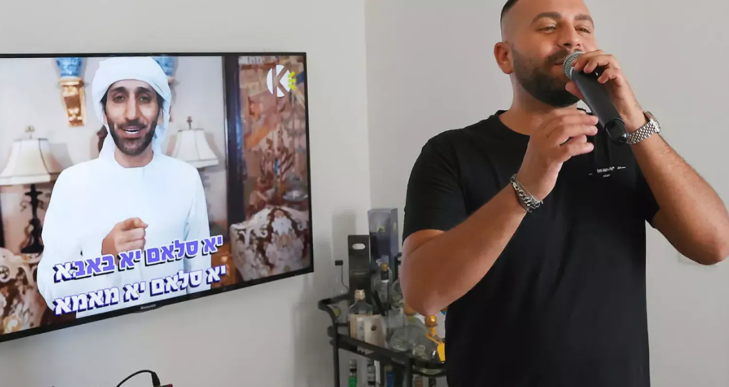 Israeli singer Elkana Marziano, 28, sings along with a video clip of his collaboration with Emirati artist Walid Aljasim (image on screen). AFP