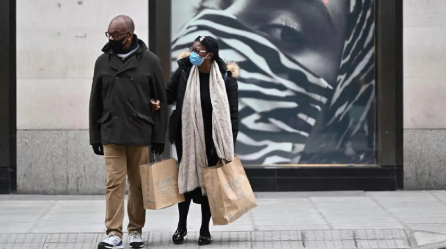 Londra’daki Oxford Caddesi'nde dün alışveriş yaparken koronavirüsten korunmak için maske takan iki vatandaş. (AFP)