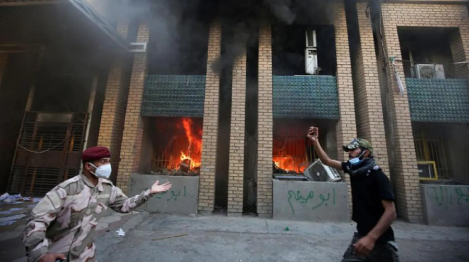 A member of the Iraqi security forces intervenes as demonstrators, supporters of the PMF, burn down the Kurdish Democratic Party's headquarters in the capital Baghdad on October 17, 2020. (Photo by AHMAD AL-RUBAYE / AFP)
