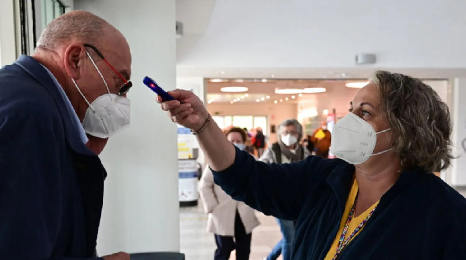 سيدة إيطالية تقيس درجة حرارة رجل لدى وصوله إلى مستشفى في ميلانو أمس (أ.ف.ب)