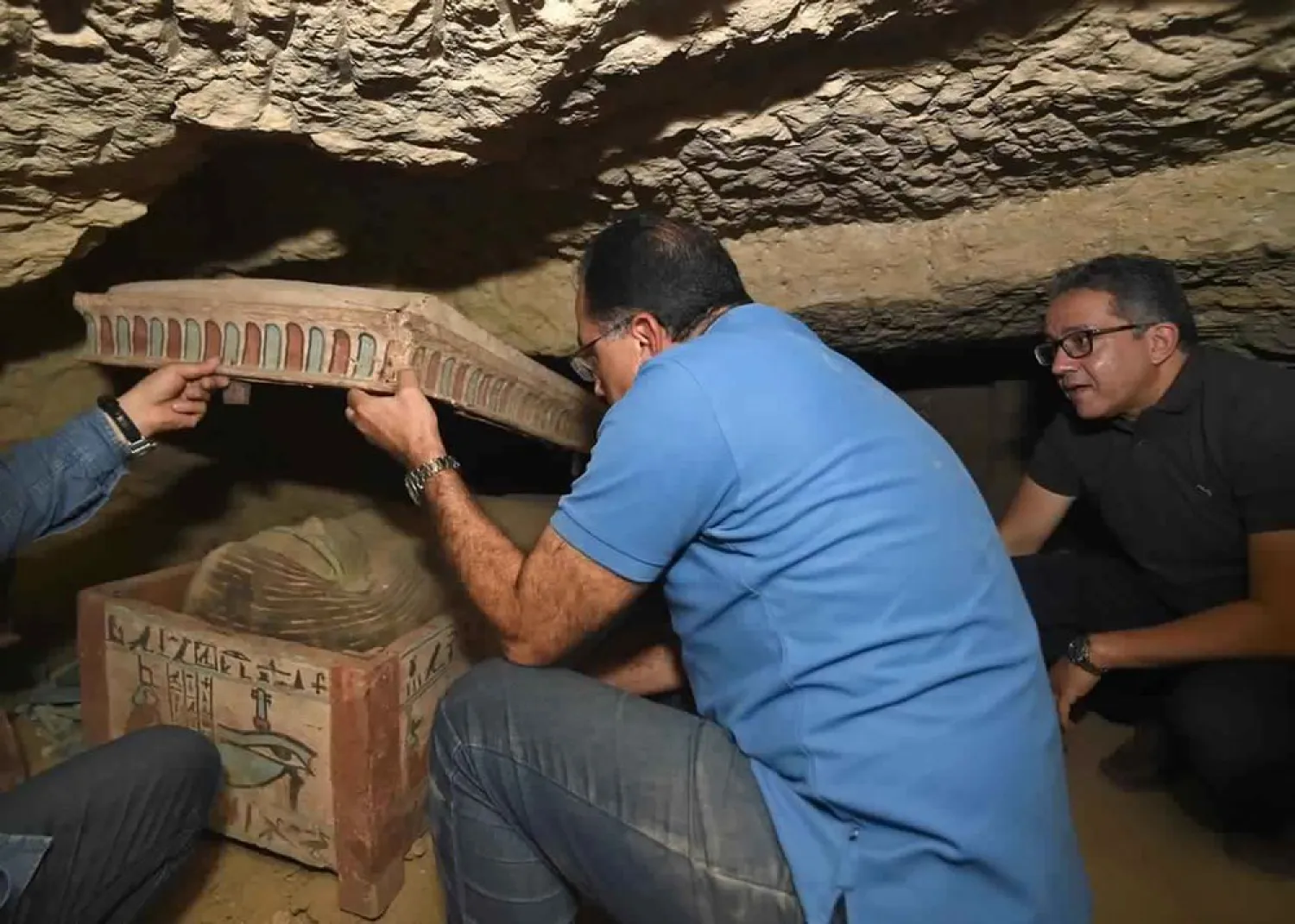 PM Mustafa Madbouly (C), Minister of Antiquities Khaled el-Anany and archeologists open a sarcophagus in a necropolis south of Cairo that is part of a recent discovery announced on Oct. 19, 2020, in Saqqara. (AP)