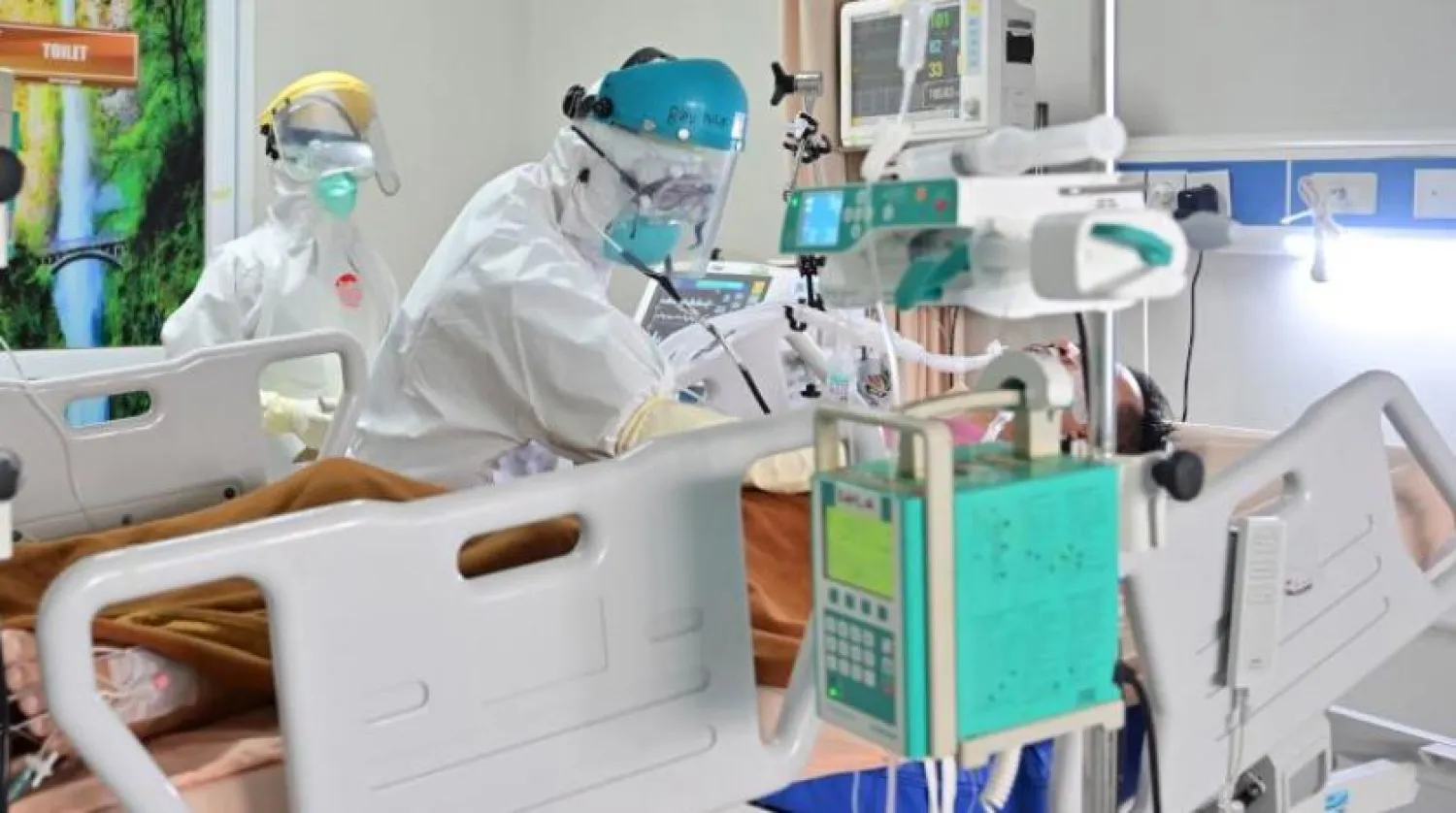 Endonezya'daki bir hastanenin yoğun bakım ünitesindeki doktor koronavirüslü bir hastayı kontrol ediyor (AFP)