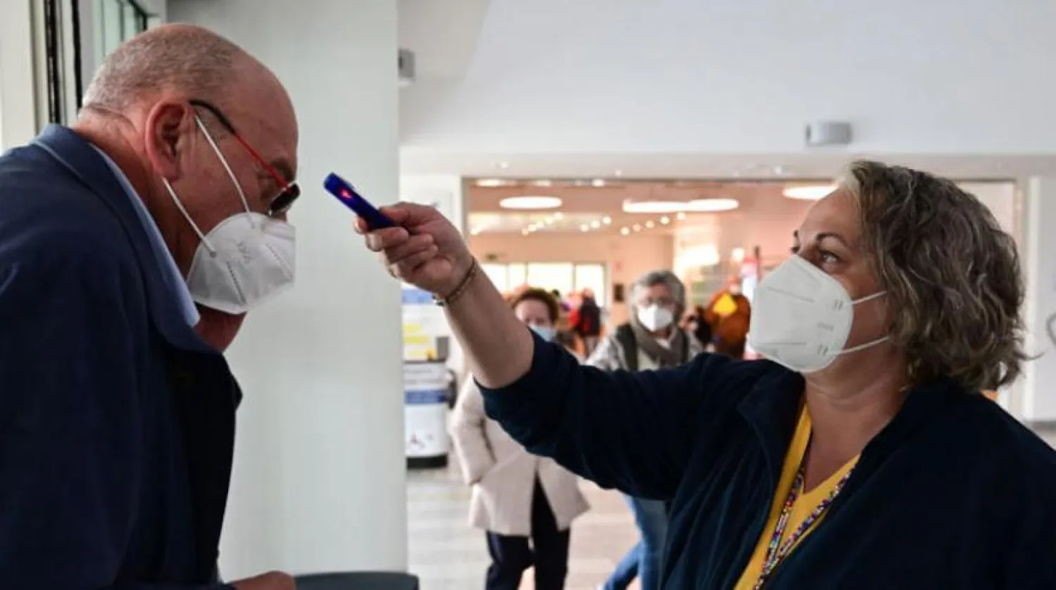 İtalya’da görevli bir kadın dün Milano'da hastaneye gelen bir vatandaşın ateşini ölçüyor (AFP)