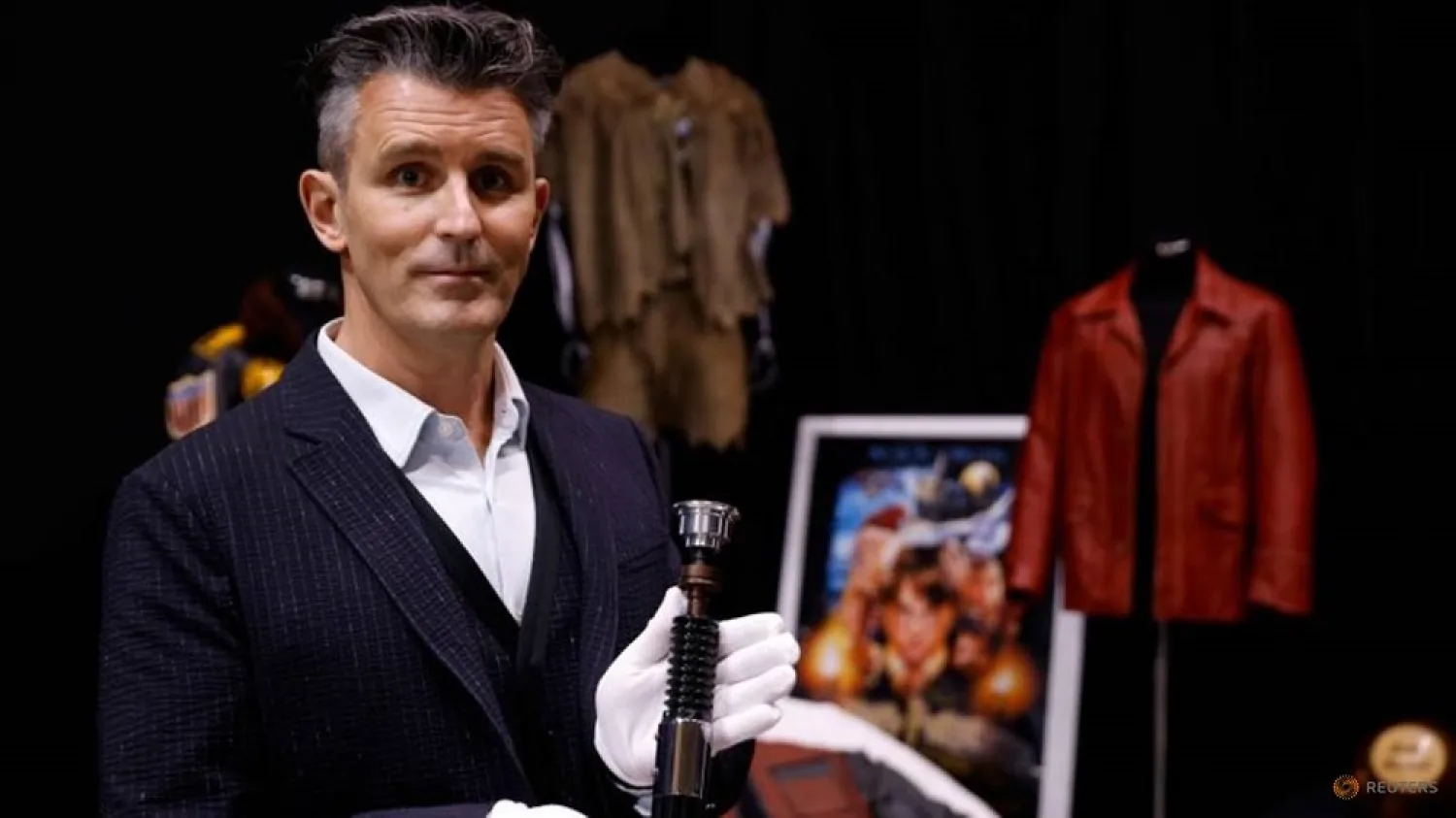 Stephen Lane, CEO of Prop Store, poses for a photograph with Obi-Wan Kenobi's Hero Lightsaber from Star Wars Revenge of the Sith. (Reuters)