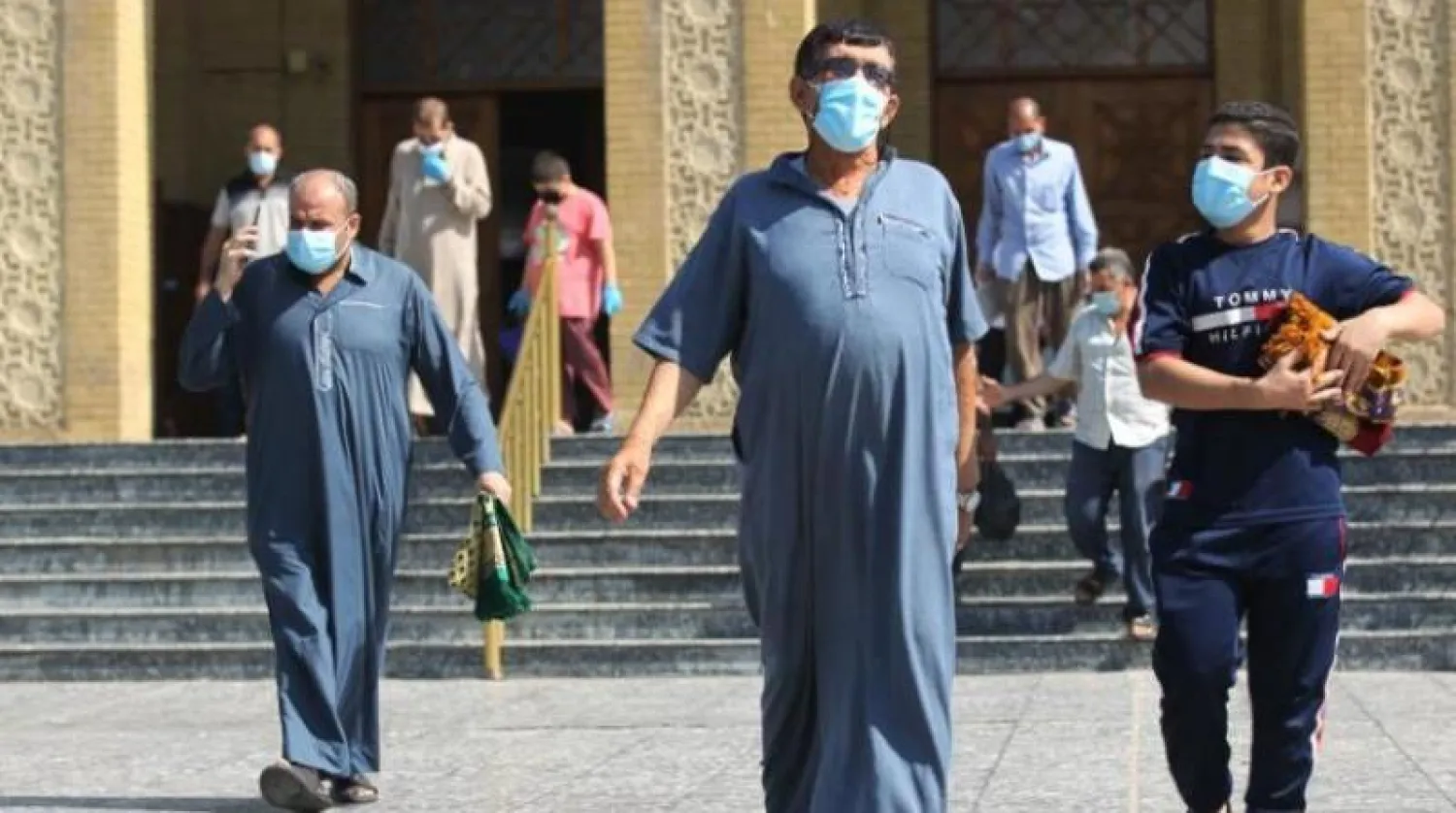 عراقيون يرتدون الأقنعة الواقية خارج مسجد «الفردوس» ببغداد (أ.ف.ب)