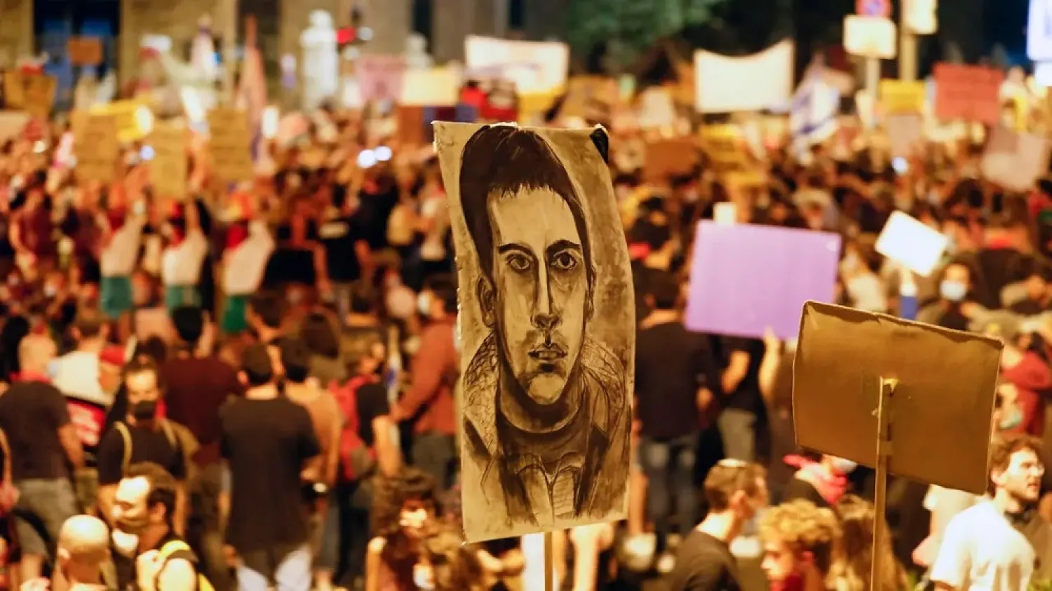 Israeli protesters raise a portrait of Iyad Hallak as they protest against Israel's government near Prime Minister Benjamin Netanyahu's residence in Jerusalem. (AFP)