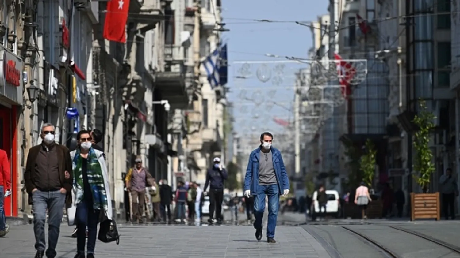 People wear face masks as they walk down the Istiklal avenue on April 14, 2020 in Istanbul. (AFP)