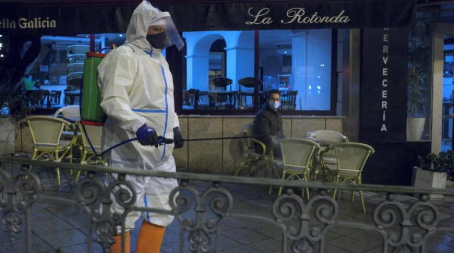 Bir temizlik işçisi, İspanya'nın kuzeybatısındaki Galiçya'da bir caddeyi dezenfekte ediyor (EPA)
