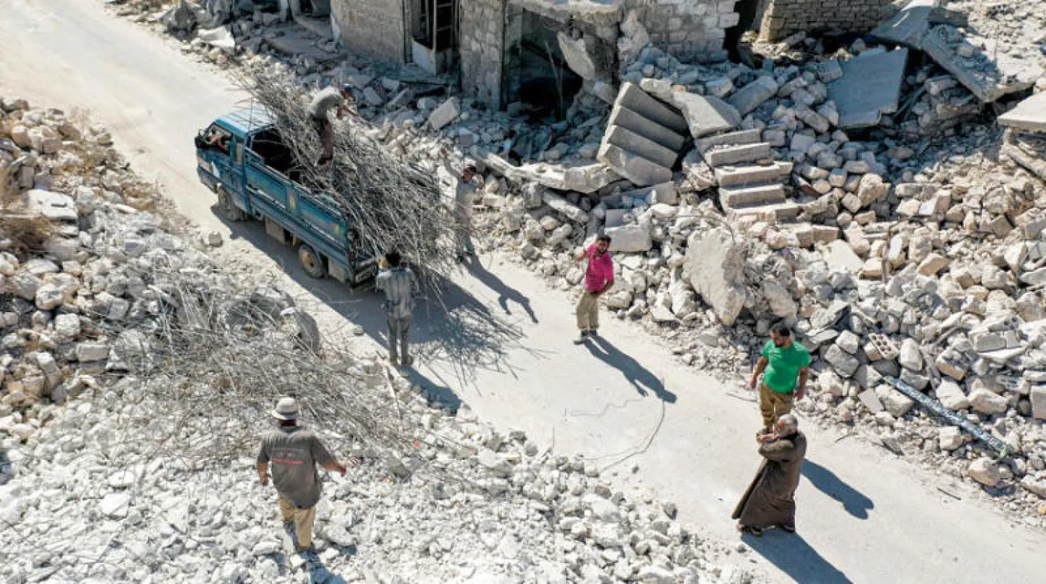 سوريون وسط الدمار في جبل الزاوية بإدلب شمال غربي البلاد (أ.ف.ب)