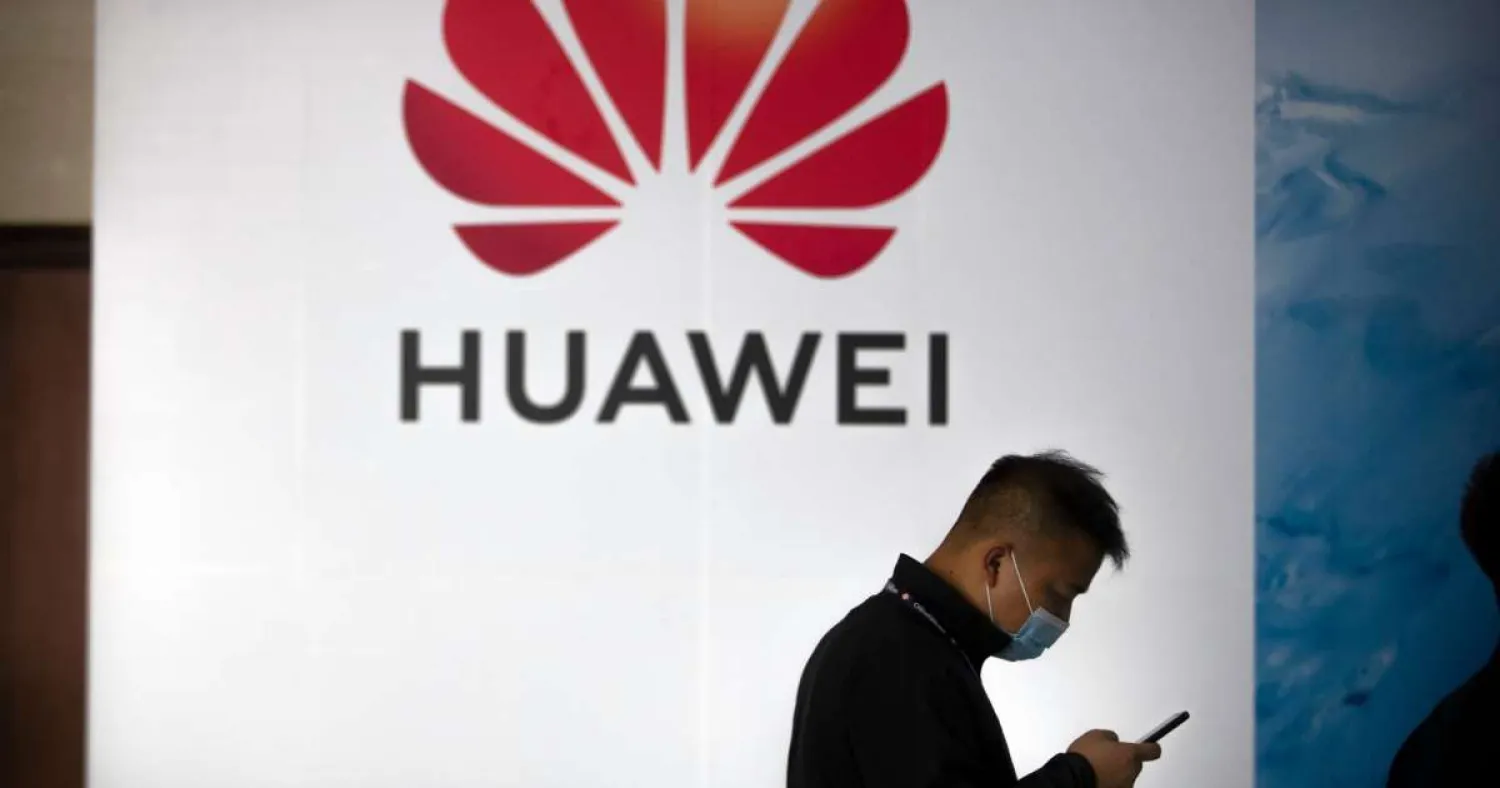 In this Oct. 14, 2020, file photo, a man wearing a face mask to protect against the coronavirus walks past a billboard advertising Chinese technology firm Huawei at the PT Expo in Beijing. (AP Photo/Mark Schiefelbein, File)