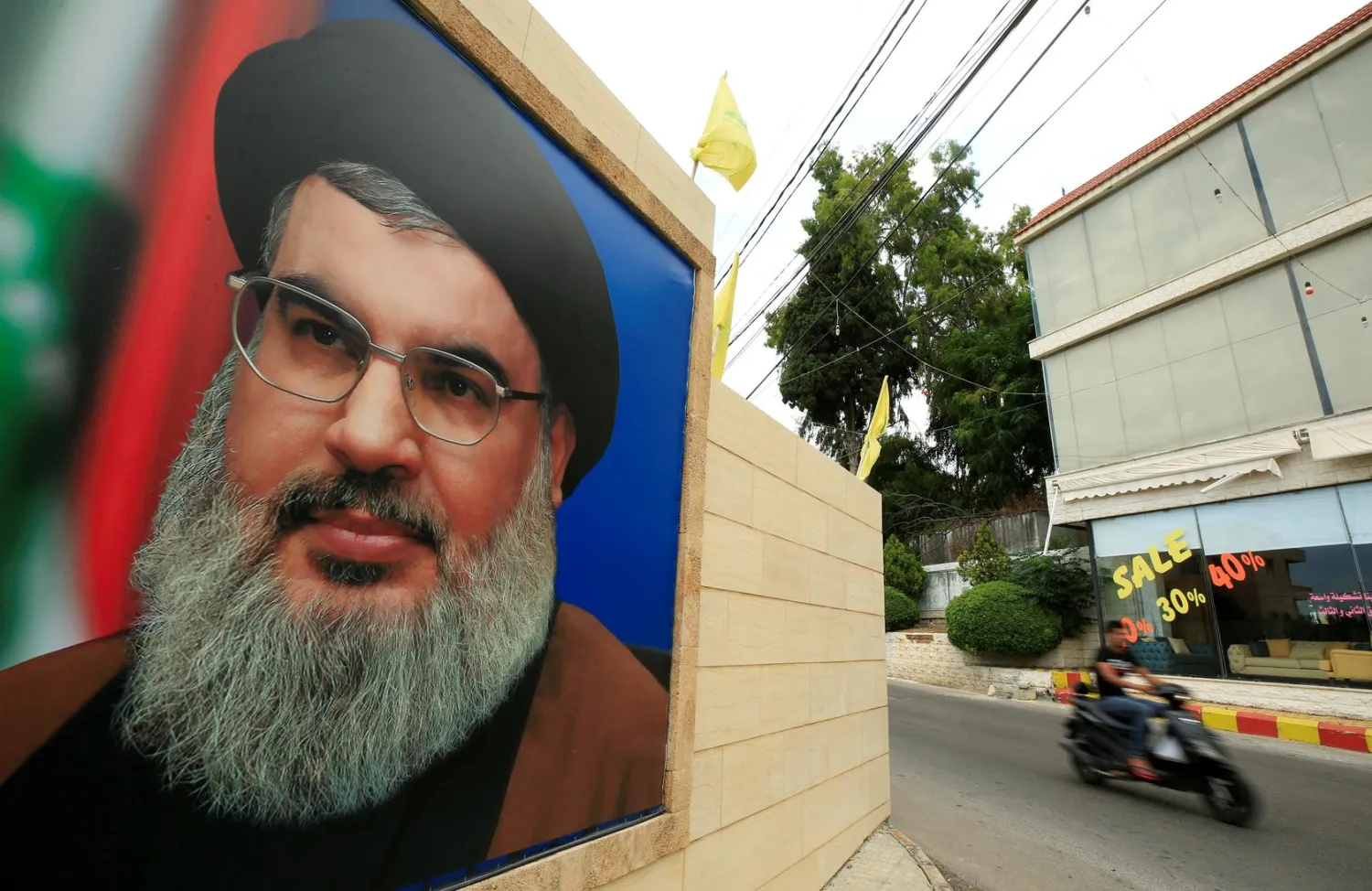 FILE PHOTO: A man rides a motorbike past a picture of Lebanon's Hezbollah leader Hassan Nasrallah, near Sidon, Lebanon July 7, 2020. REUTERS/Ali Hashisho/File Photo