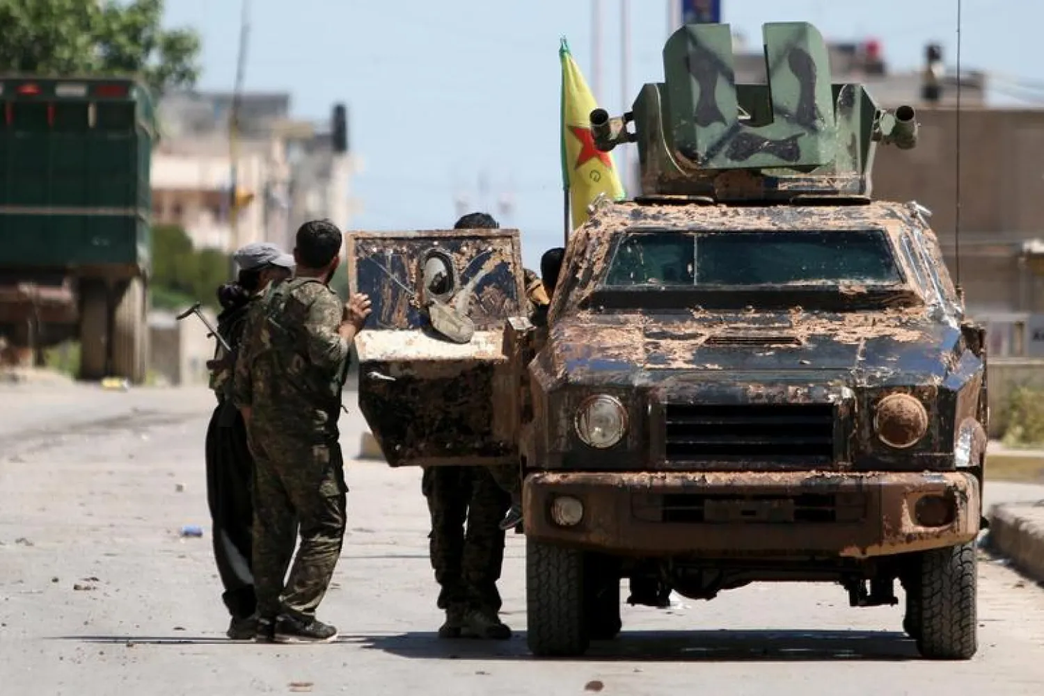 Kurdish fighters from the People's Protection Units (YPG) stand near a military vehicle in the southeast of Qamishli city, Syria (Reuters)