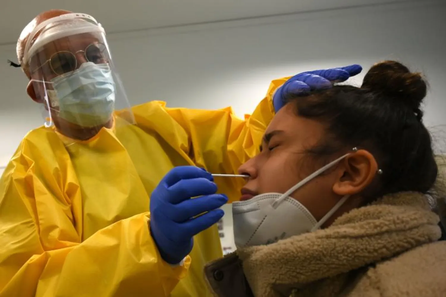 ممرض يأخذ مسحة من مريضة لإجراء اختبار سريع لفيروس كورونا في مركز الرعاية الأولية في برشلونة (ا.ف.ب)