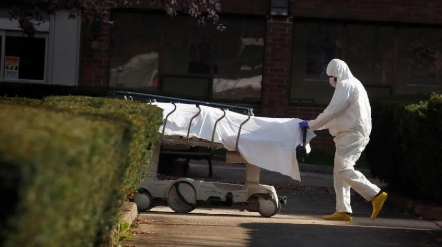 New York’taki bir sağlık çalışanı bir koronavirüs kurbanının cesedini taşıyor (Reuters)