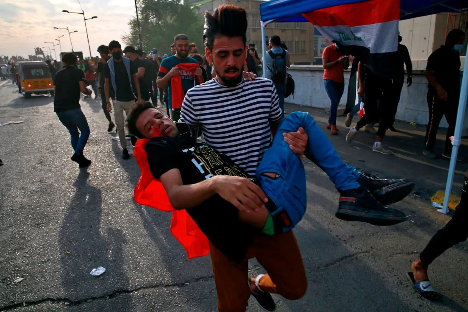 An injured protester is rushed to a hospital during clashes with security forces on the closed Joumhouriya bridge that leads to the Green Zone government areas, in Baghdad, Iraq, Sunday, Oct. 25, 2020. (AP Photo/Khalid Mohammed)