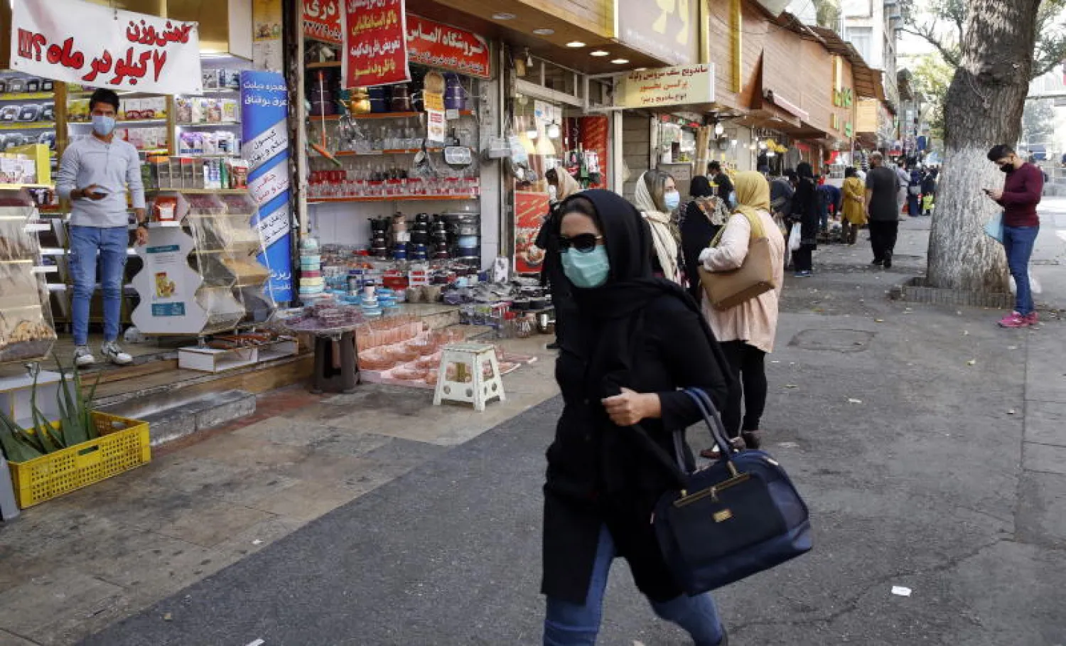 سيدة إيرانية ترتدي قناعاً واقياً في أحد أسواق طهران (إ.ب.أ)