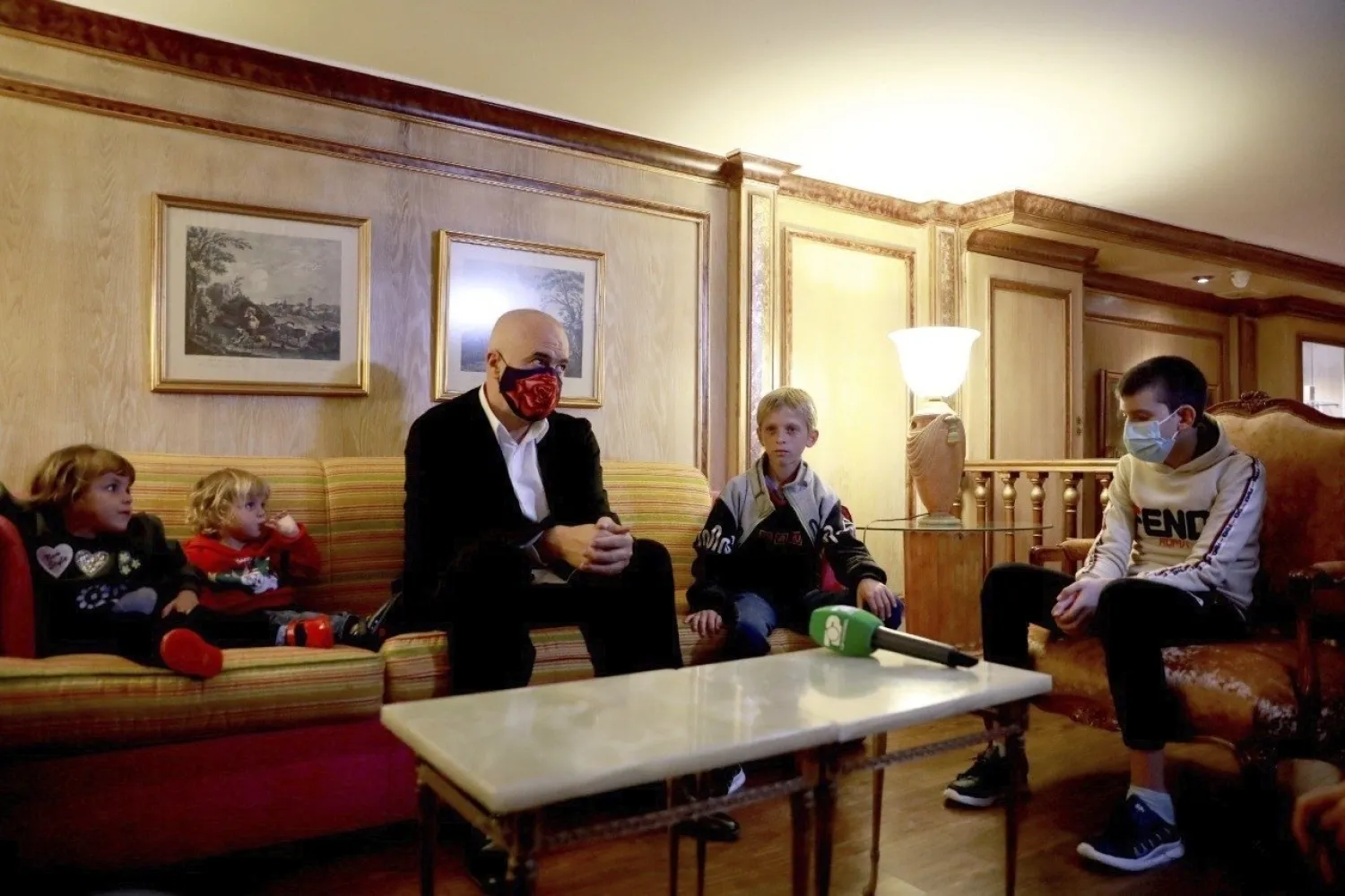 In this photo provided by the Albanian Prime Minister's office, Albania's Prime Minister Edi Rama sits at a hotel in Beirut, Lebanon, Monday, 26, 2020, with Albanian children as part of an operation to take them back home to Albania from Al Hawl, northern Syria. (Albanian Prime Minister's office via AP)

