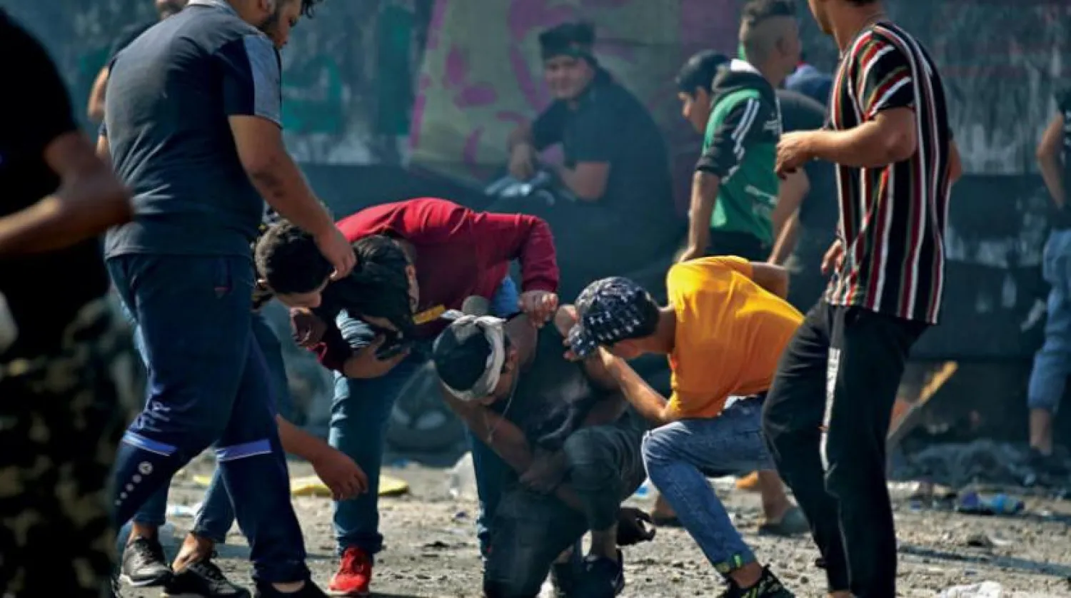 Iraqi protesters assisting one of their comrades who was injured in clashes with security forces in Baghdad yesterday (AFP)

