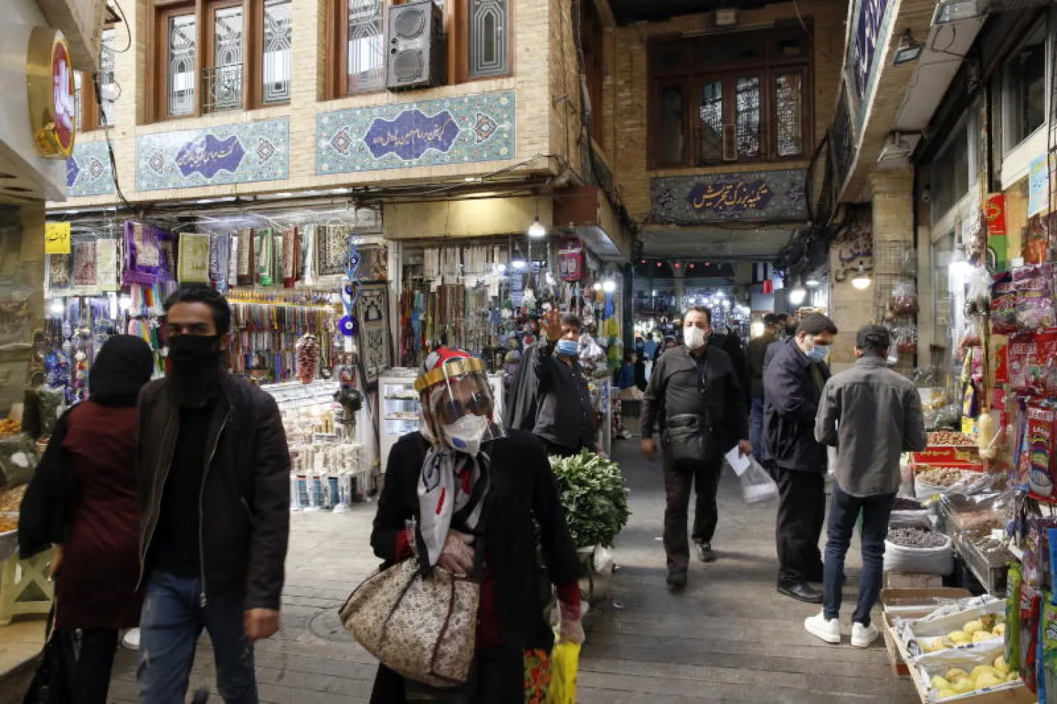 إيرانيون يرتدون أقنعة الوجه في إحدى الأسواق بطهران (إ.ب.أ)