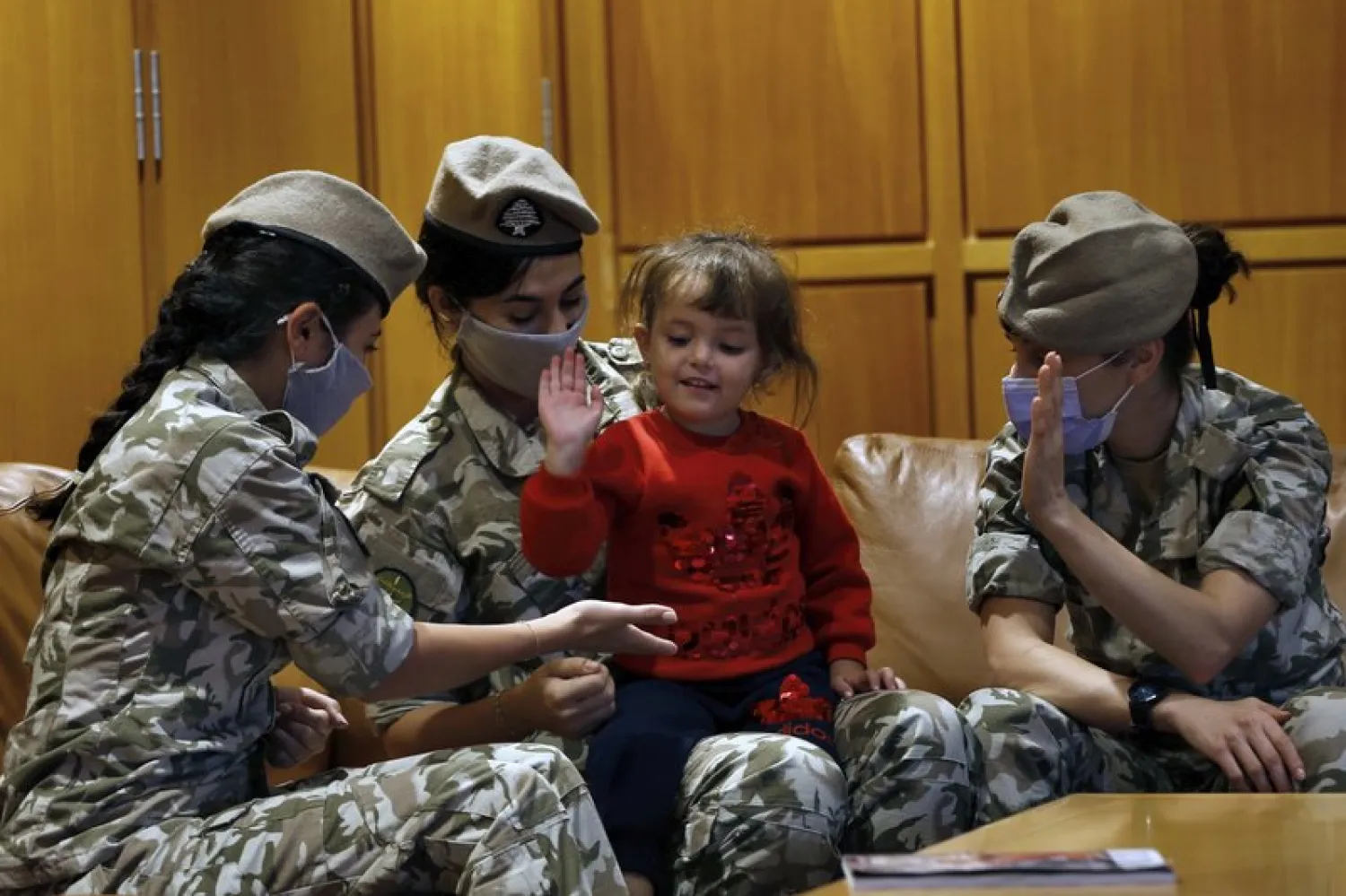 Members of the Lebanese General Security forces play with an Albanian child during an operation to take them back home to Albania from al-Hol, northern Syria, at the Rafik Hariri International Airport in Beirut, Lebanon, Tuesday, Oct. 27, 2020. (AP Photo/Bilal Hussein)