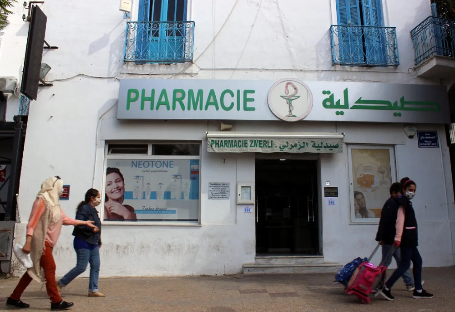 People, wearing masks against the coronavirus, walk past a pharmacy, amid concerns over the spread of COVID-19 in Tunis, Tunisia October 7, 2020. (Reuters)