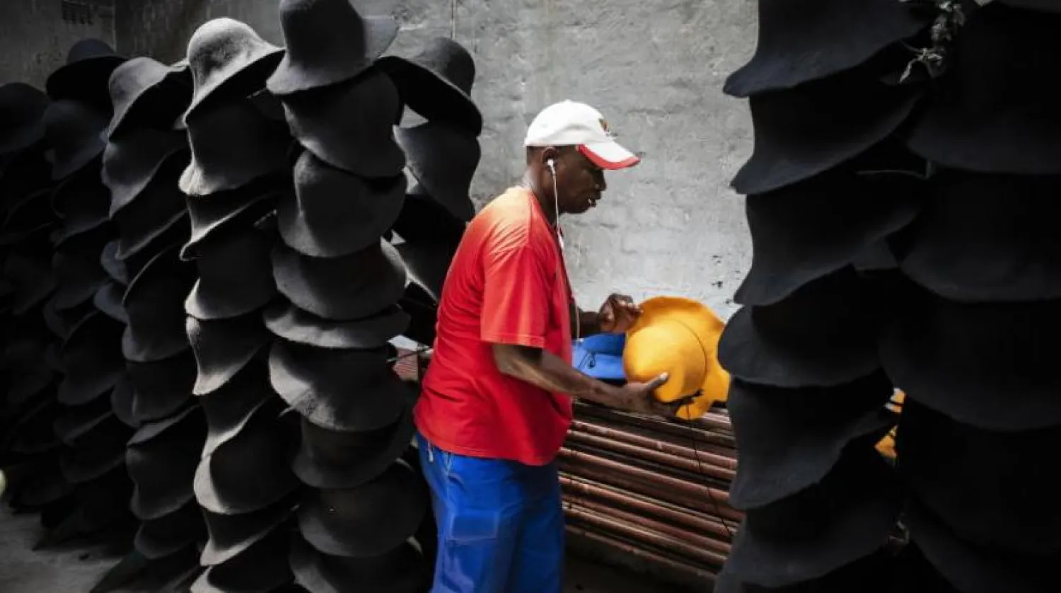 Güney Afrika’da bir şapka fabrikasında çalışan bir işçi (EPA)
