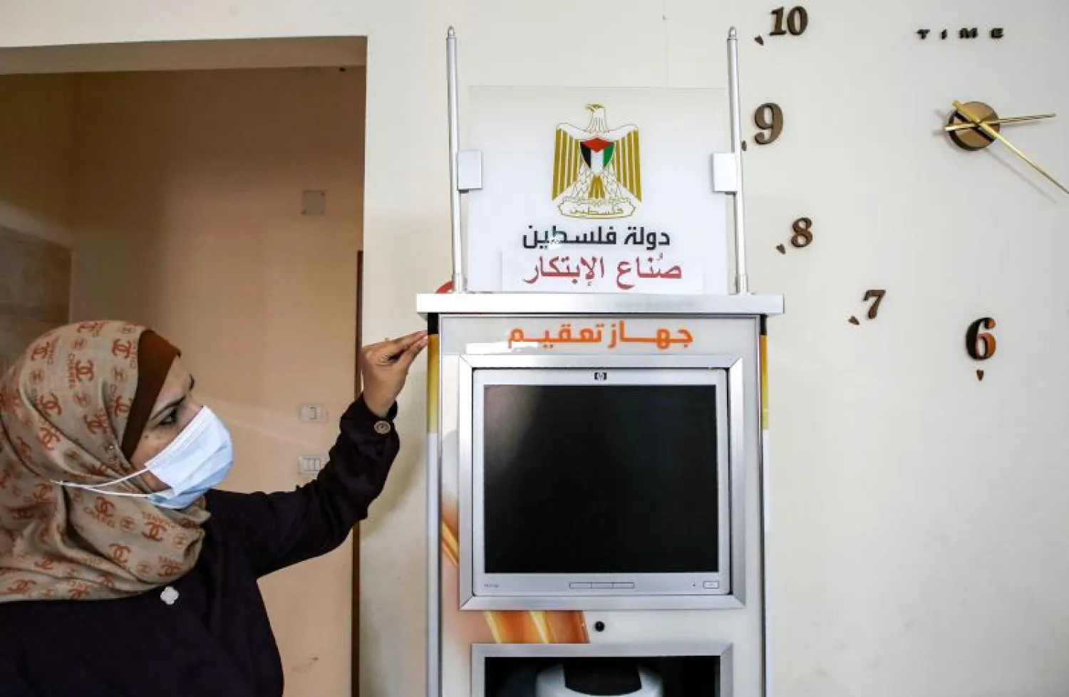 الفلسطينية هبة الهندي مع جهاز التعقيم (أ.ف.ب)