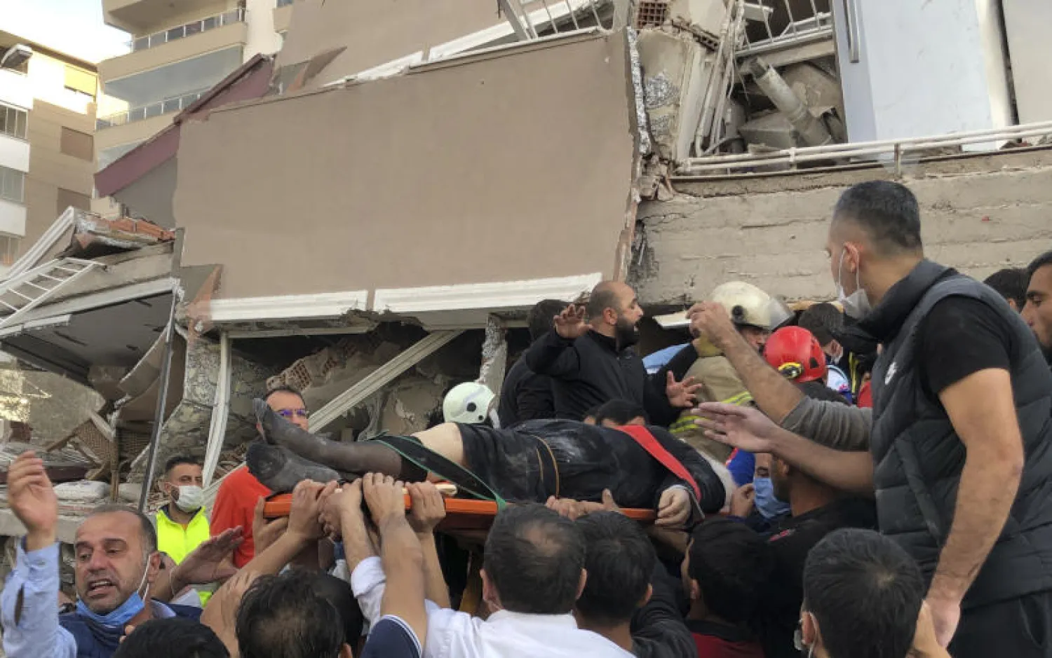 نقل جريح عثر عليه بين حطام مبنى منهار في إزمير التركية (أ.ب)