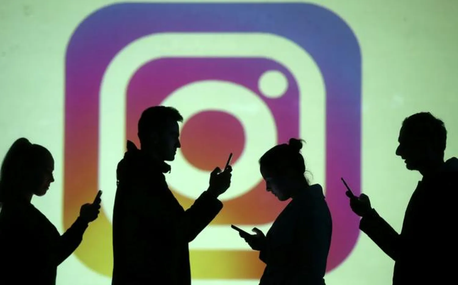 FILE PHOTO: Silhouettes of mobile users are seen next to a screen projection of the Instagram logo in this picture illustration taken March 28, 2018. REUTERS/Dado Ruvic/Illustration/File Photo