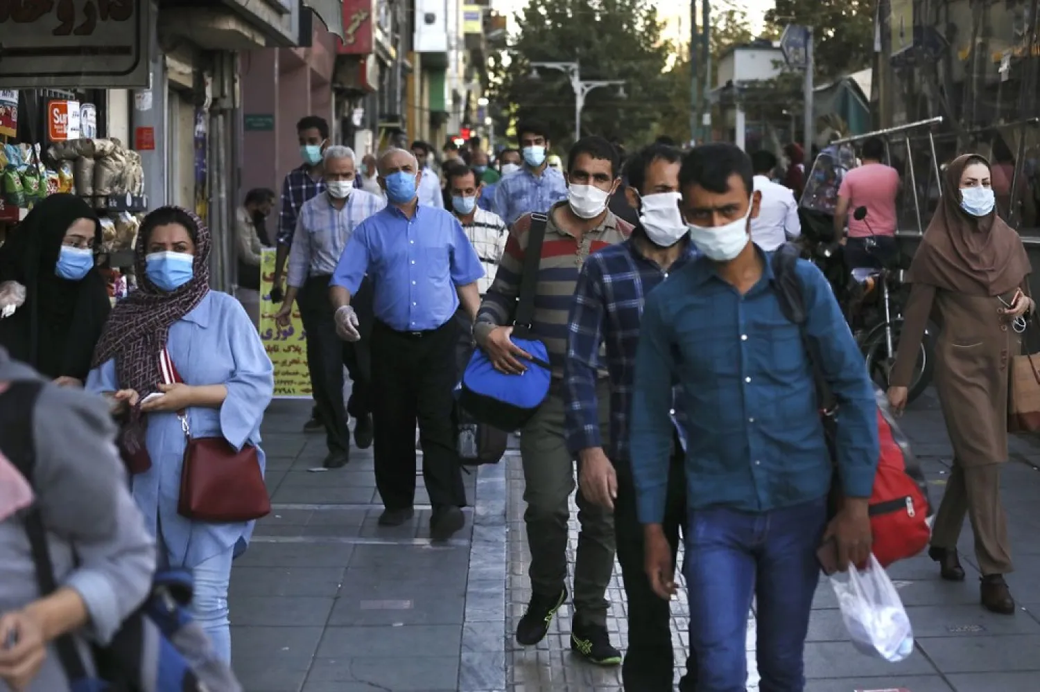 People wearing protective face masks to help prevent spread of the coronavirus walk on a sidewalk of a commercial street in Tehran, Iran, Sept. 20, 2020. (AP)