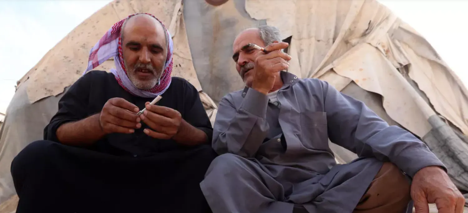 Elderly displaced Syrian men sit in front of a tent to smoke, in an overcrowded displacement camp near the village of Qah near the Turkish border in the northwestern Idlib province, on October 28, 2020, during the novel coronavirus pandemic crisis. (Photo by Ahmad al-ATRASH / AFP)