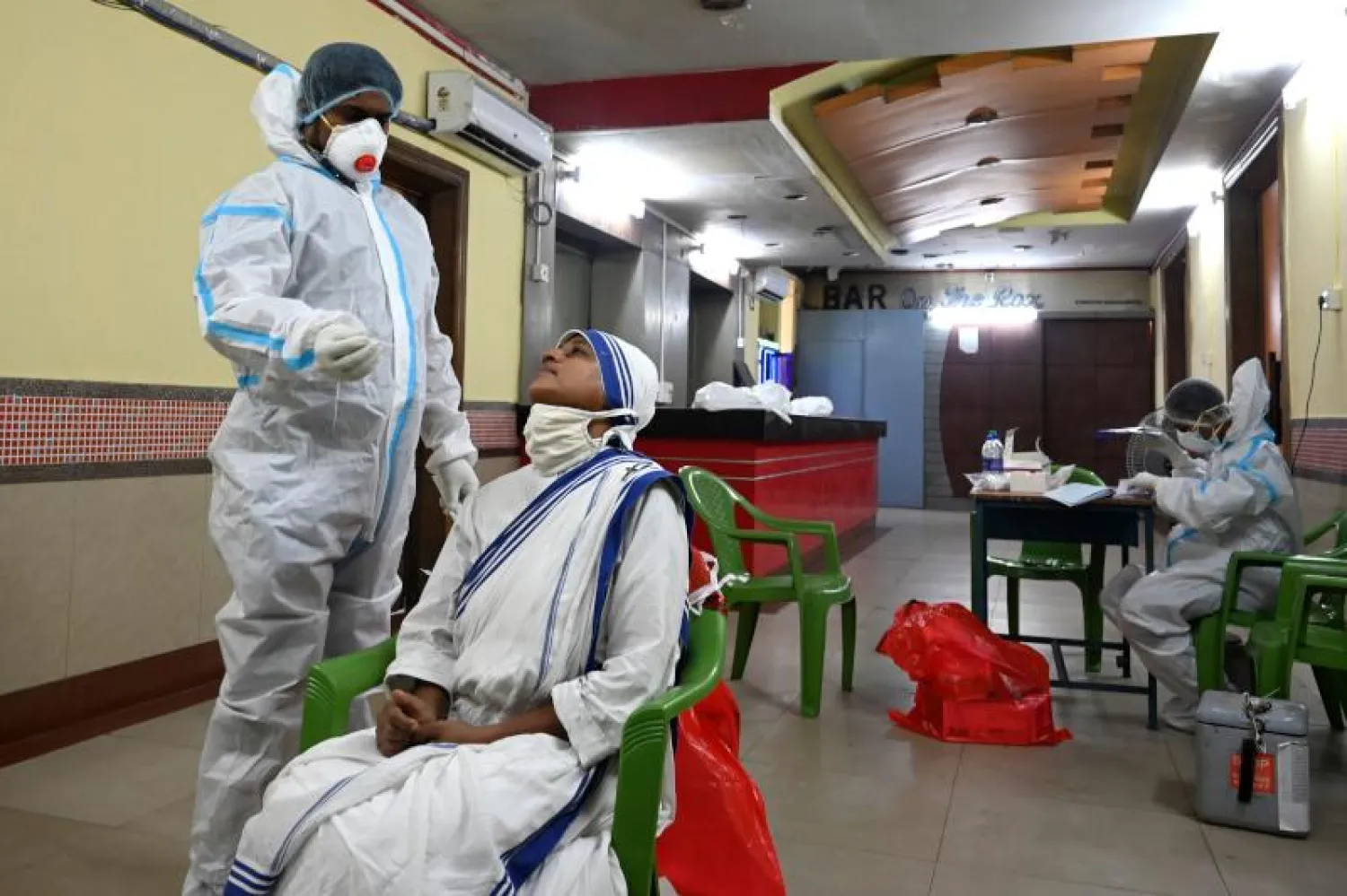 عاملة بالقطاع الطبي تقوم بإجراء اختبار «كورونا» لإحدى الراهبات في الهند (أ.ف.ب)