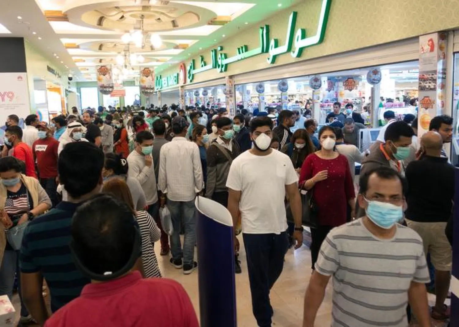 FILE: People wearing protective masks, following the coronavirus outbreak, walk at a supermarket in Salmiya, after Kuwait's government announced mandatory work leave for all people in Kuwait, March 11, 2020. REUTERS/Stephanie McGehee
