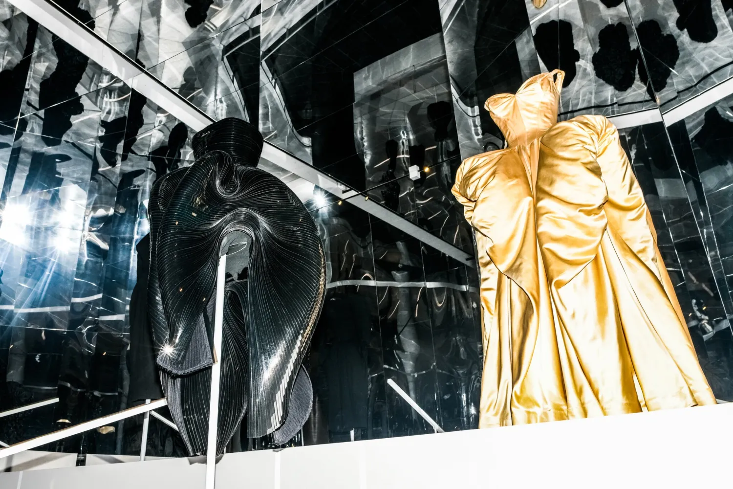 Each costume is paired with an alternative work that reveals fashion’s relationship to time. Left, an Iris van Herpen dress, from 2012, with Alien-like appendages, alongside a cream 1951 gown from Charles James with tentacle-like protrusions.Credit...Dolly Faibyshev for The New York Times